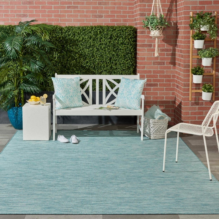 8x10 aqua blue indoor outdoor area rug from the Positano collection by Nourison featuring a modern solid design with subtle woven texture. Durable polypropylene machine-made rug designed for patios, decks, porches, living rooms, bedrooms, and dining rooms. Lightweight, stain-resistant, and easy-clean rug ideal for high-traffic areas and homes with pets or kids. Modern coastal rug perfect for contemporary, minimalist, and boho home decor.
