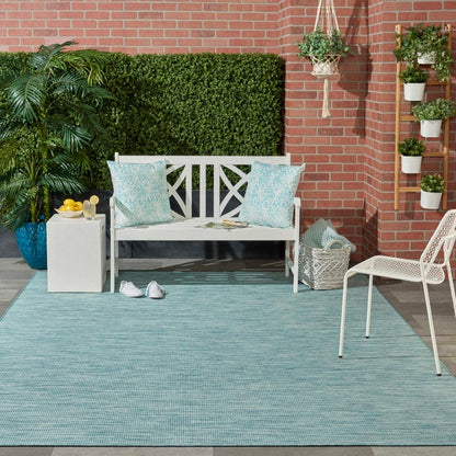 8x10 aqua blue indoor outdoor area rug from the Positano collection by Nourison featuring a modern solid design with subtle woven texture. Durable polypropylene machine-made rug designed for patios, decks, porches, living rooms, bedrooms, and dining rooms. Lightweight, stain-resistant, and easy-clean rug ideal for high-traffic areas and homes with pets or kids. Modern coastal rug perfect for contemporary, minimalist, and boho home decor.