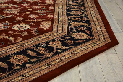 Traditional Persian-style rug with red field, navy and beige borders and gold floral motifs on light wood floor.
