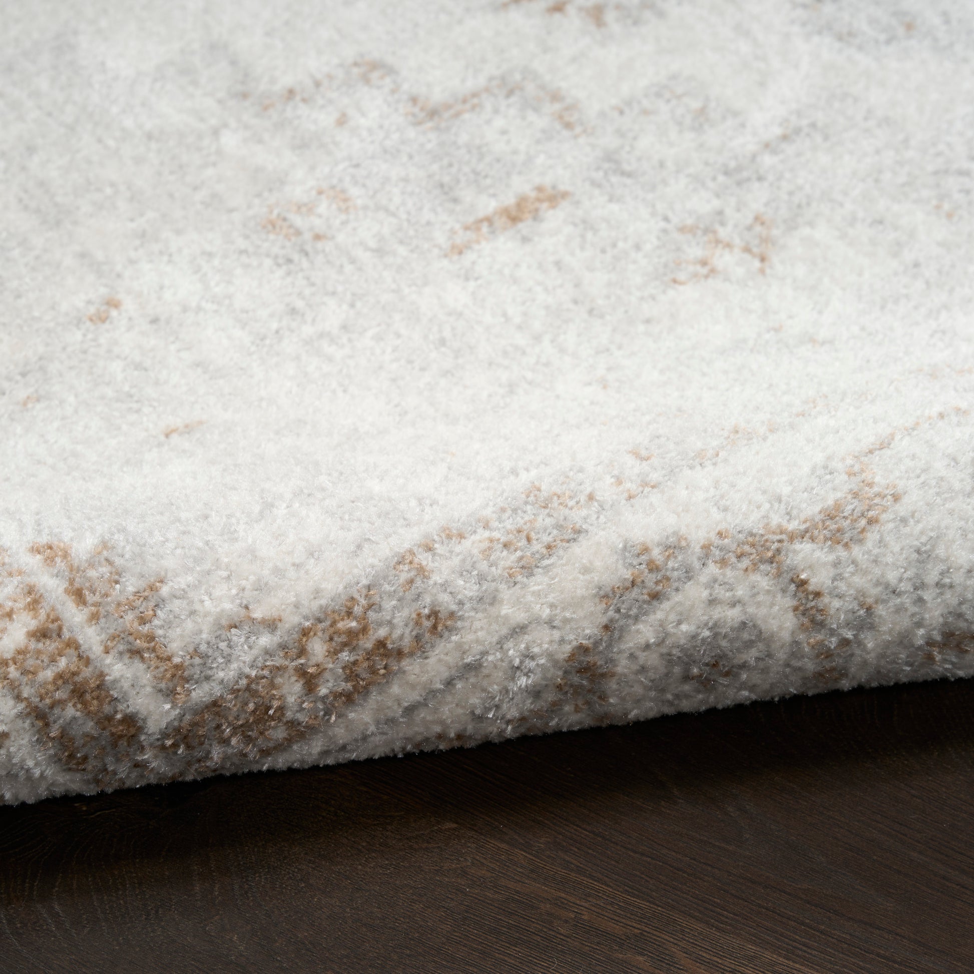 White shag rug with beige geometric lines, plush pile, folded edge on dark wood floor.