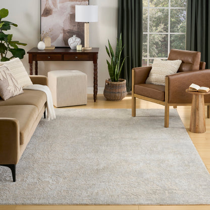 Cozy modern living room with beige sofa, brown leather armchair, light gray rug, wooden console, plants, natural light.