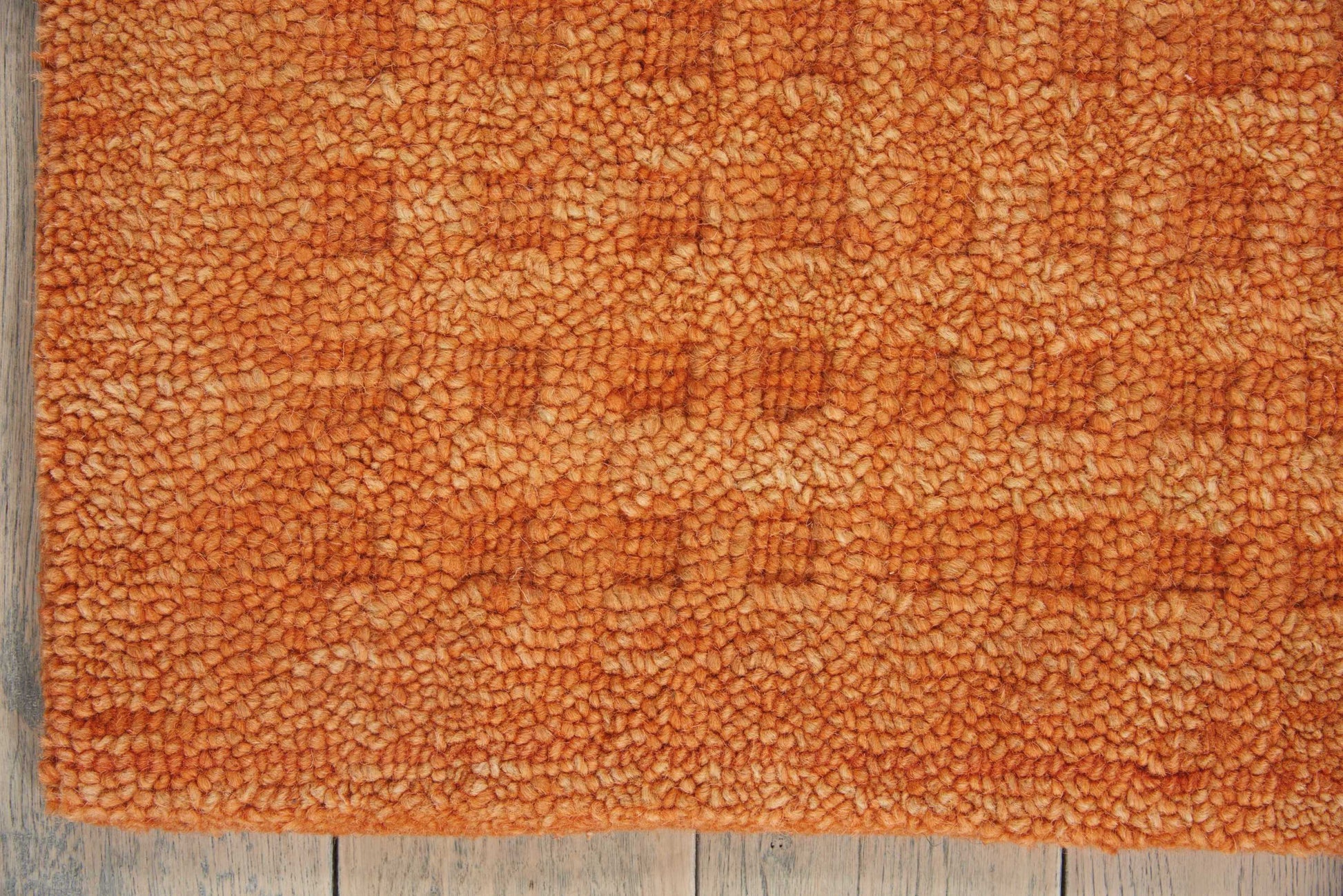 Orange shag rug with dense curly pile laid on weathered wooden floor, rectangular and cozy for living rooms.