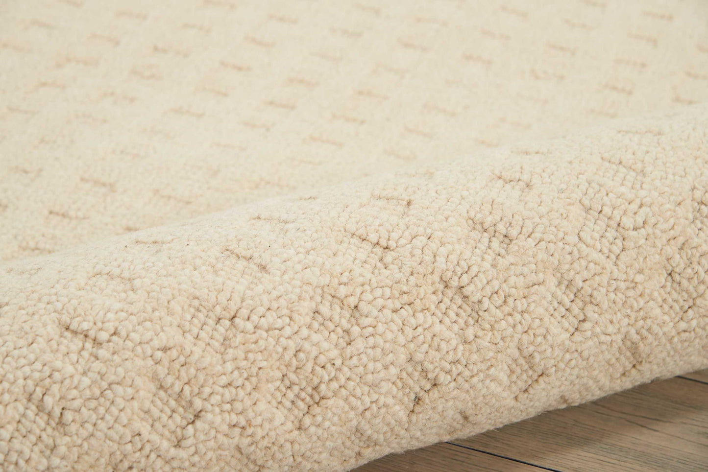 Beige shag rug with dense plush pile and soft texture on a light wood floor.