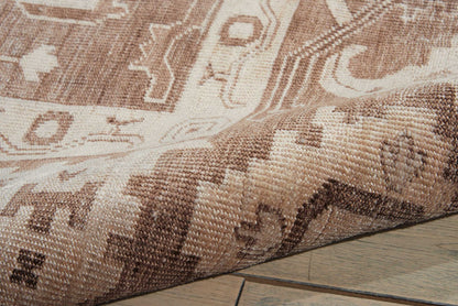 Brown and beige oriental rug with geometric motifs, woven texture, partially rolled on wooden floor