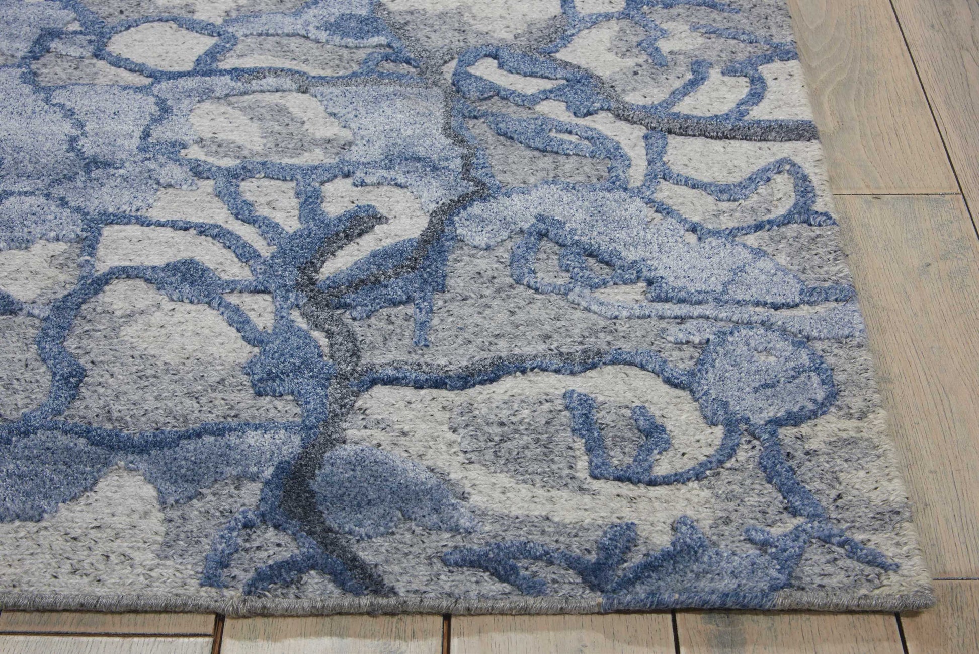 Blue-gray shag rug with an abstract branch motif on a light gray base; plush texture, 9' x 12' rectangular living room area rug.