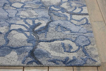 Blue-gray shag rug with an abstract branch motif on a light gray base; plush texture, 9' x 12' rectangular living room area rug.