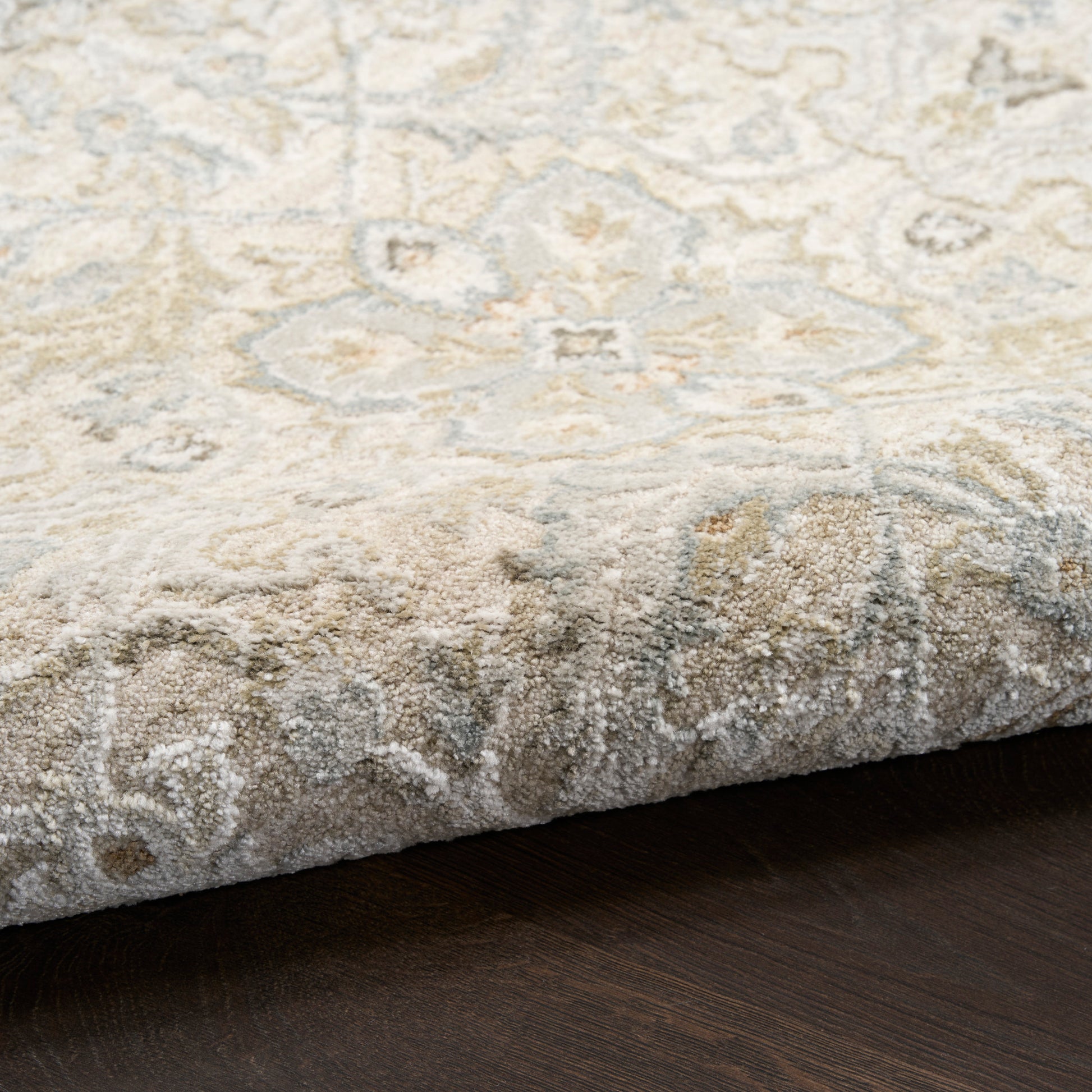 Beige and ivory Persian-style area rug with floral medallion, soft pile on dark wood floor.