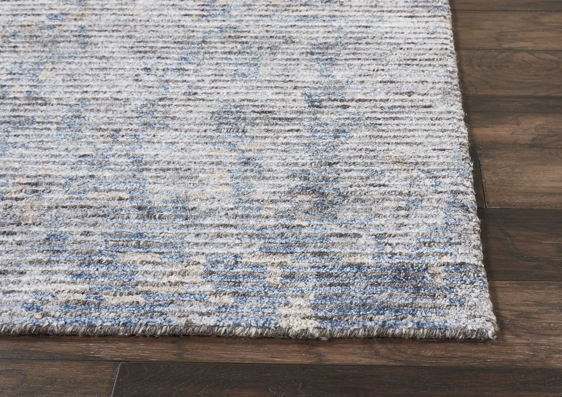 Rectangular area rug in blue and beige with a textured distressed pattern on dark wood floor.