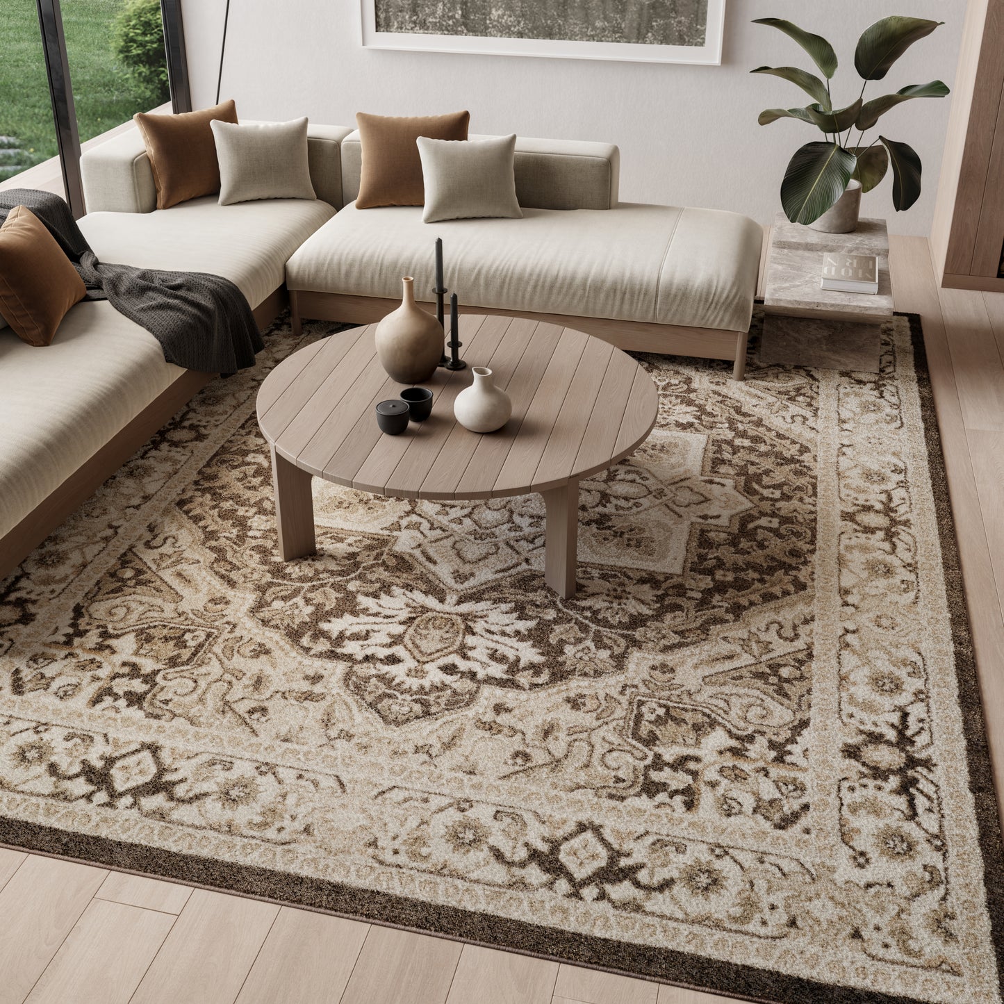 Round wooden coffee table with vases & candles in a beige sectional living room with an ornate beige rug.