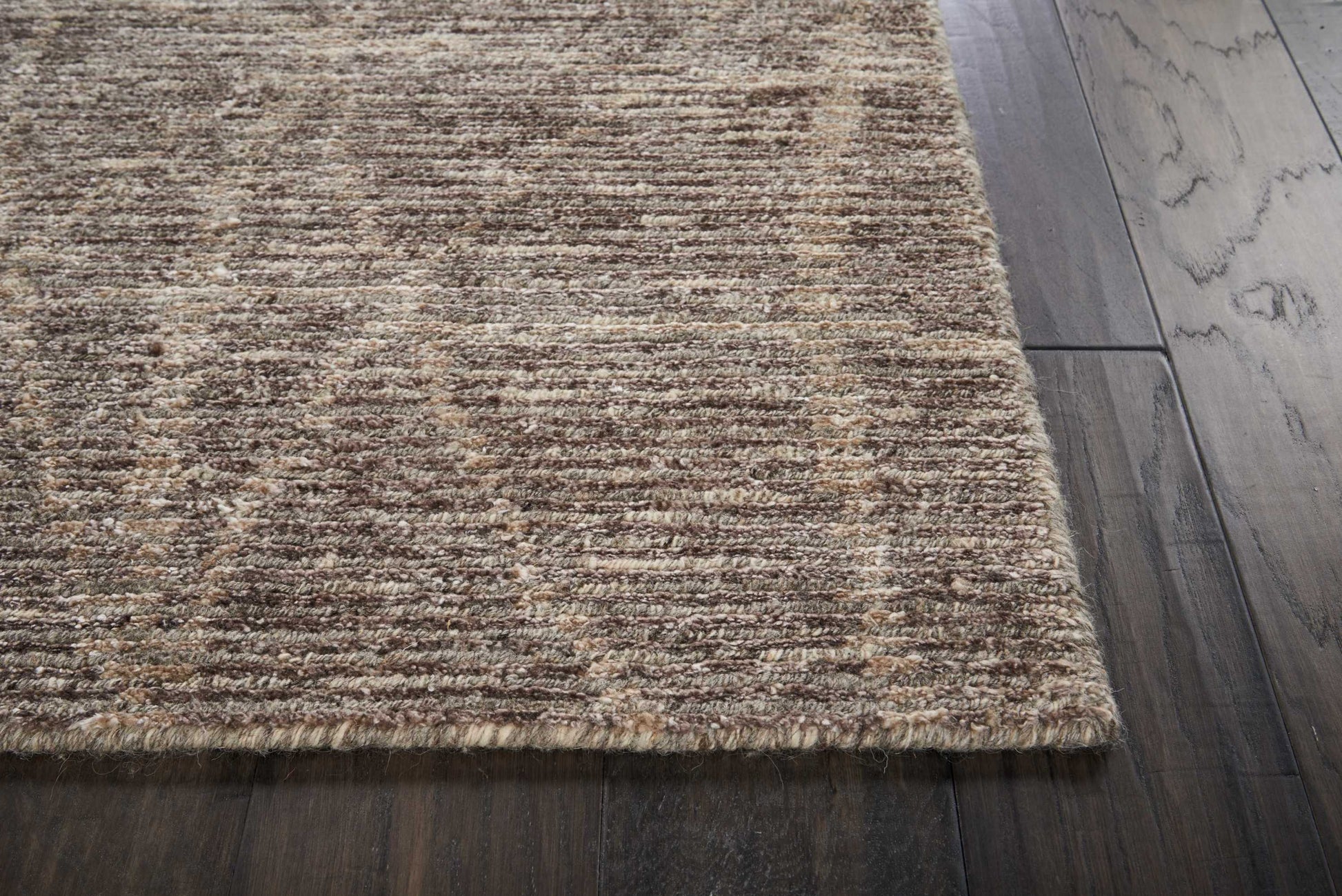 Neutral brown-beige textured area rug on dark hardwood floor.