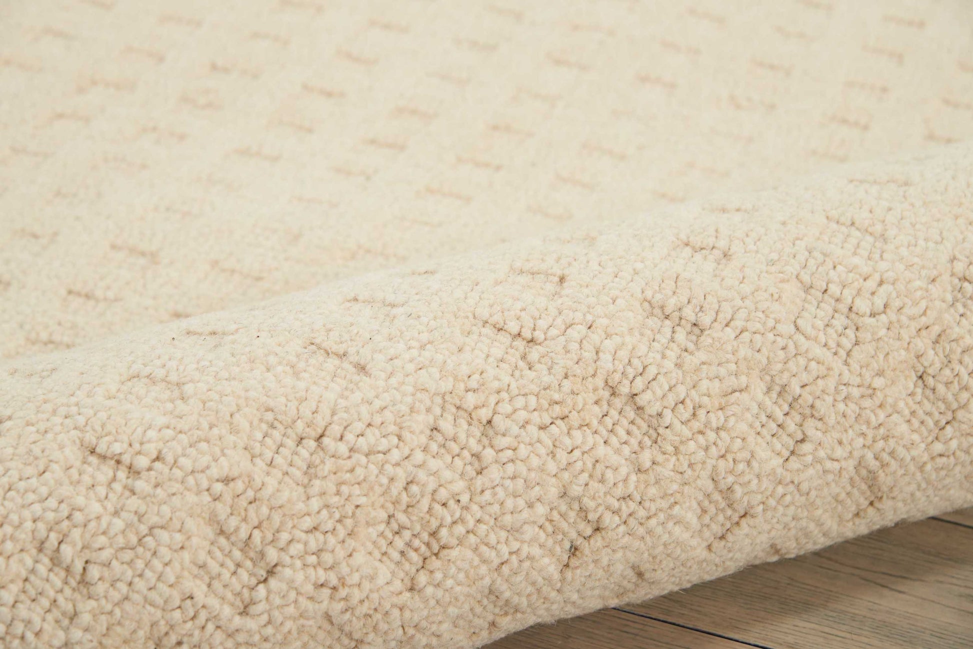 Cream beige shag rug with dense plush pile, rolled edge on light wooden floor.