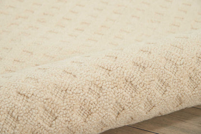 Cream beige shag rug with dense plush pile, rolled edge on light wooden floor.