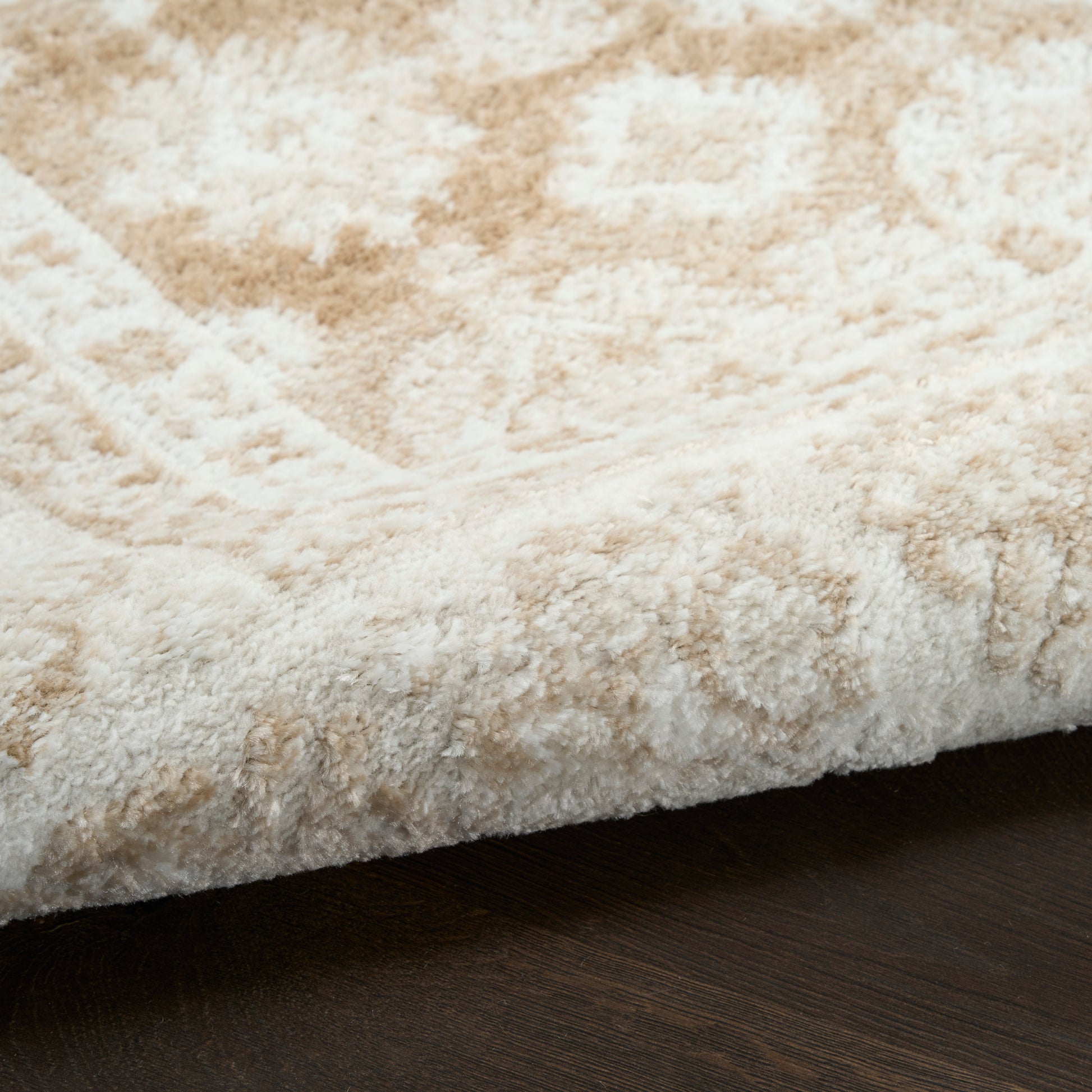Cream and beige shag rug with plush, textured pile on dark wood floor.