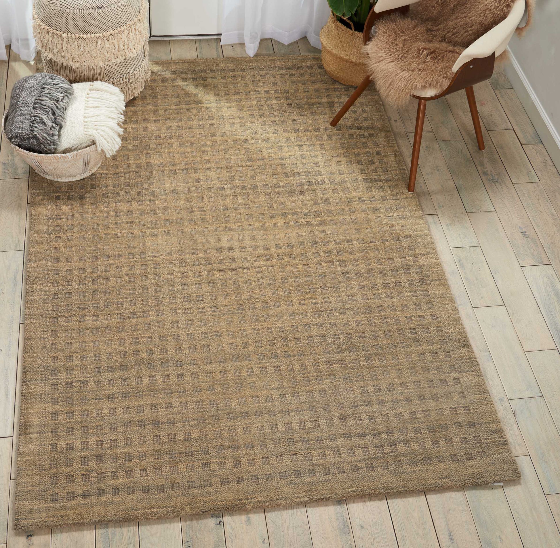 Beige woven jute rug with subtle checker pattern over wood floor; entryway with baskets, throws, and a mid-century chair.