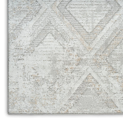 Light gray and ivory geometric patterned rug with distressed texture and plush pile.