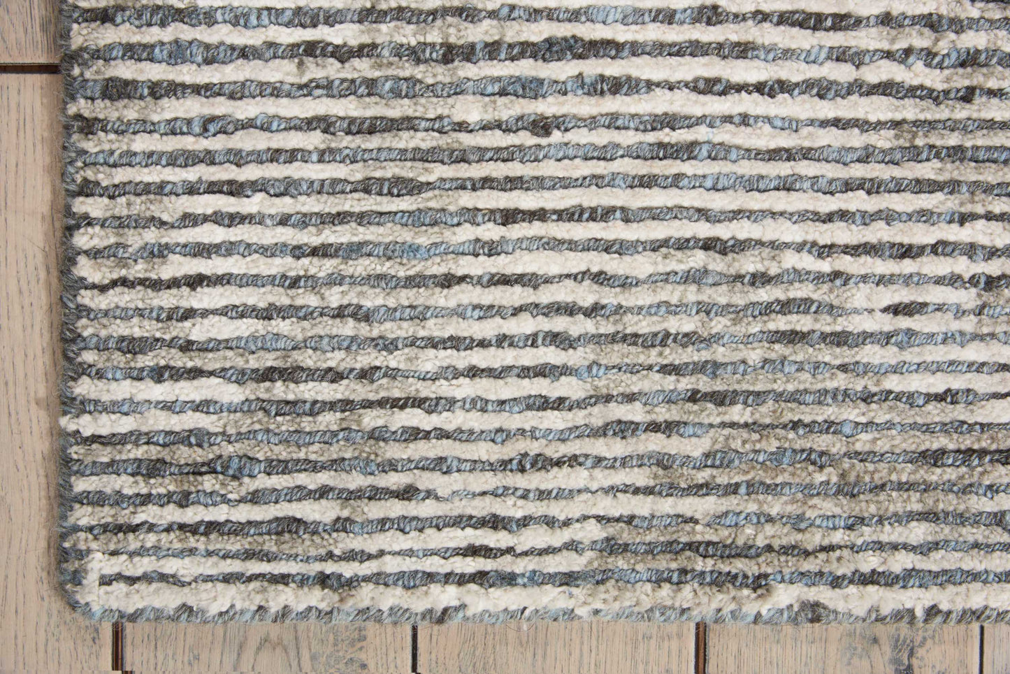 Striped shag rug with blue-gray and cream stripes on a light wood floor.