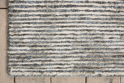 Striped shag rug with blue-gray and cream stripes on a light wood floor.
