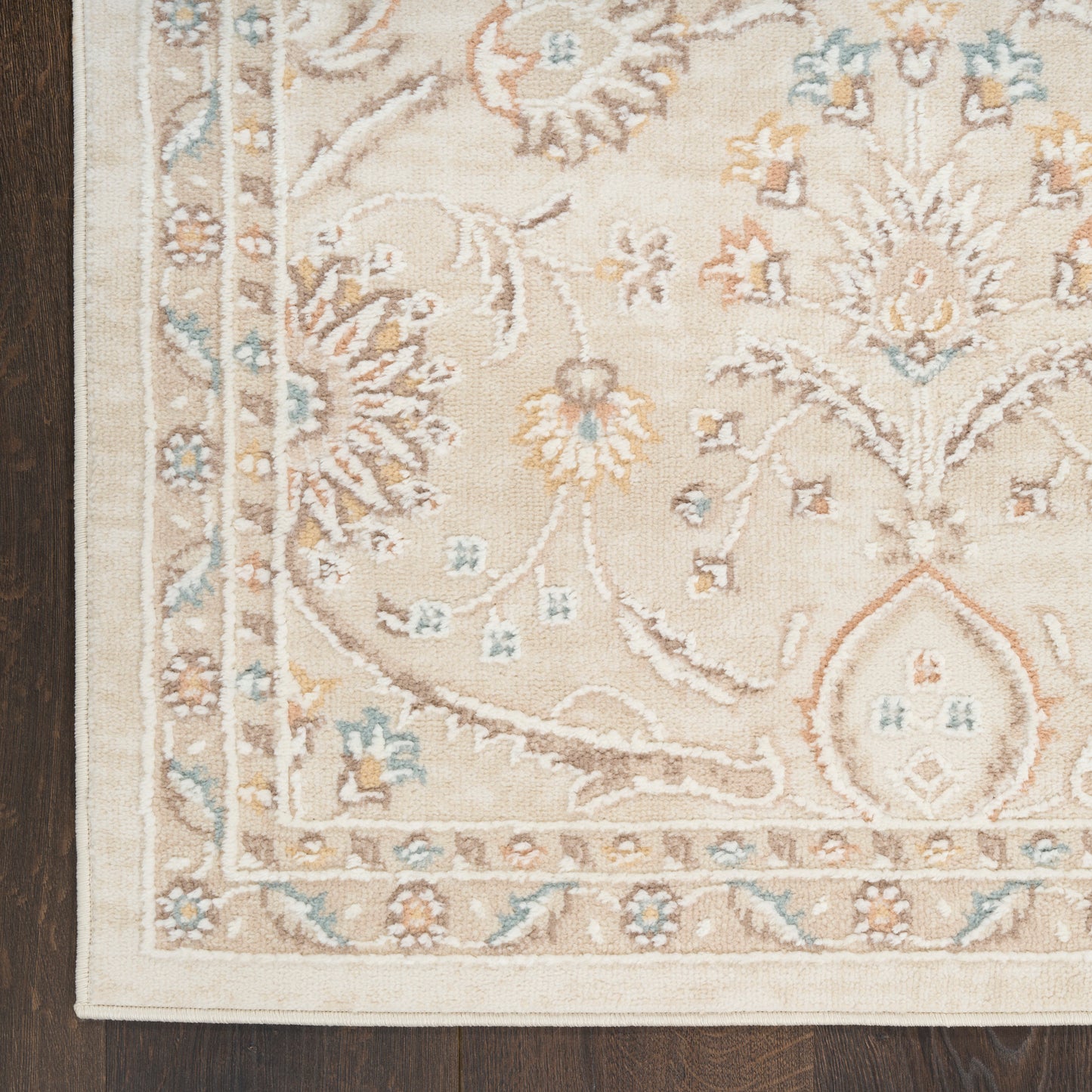 Beige oriental area rug with pale blue, ivory and tan floral motifs, ornate border and corner arch, on dark wood floor.