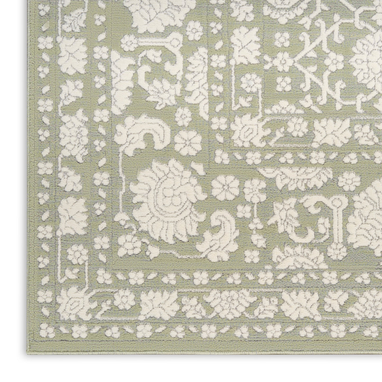 Sage green area rug with white embossed floral damask pattern and decorative border.