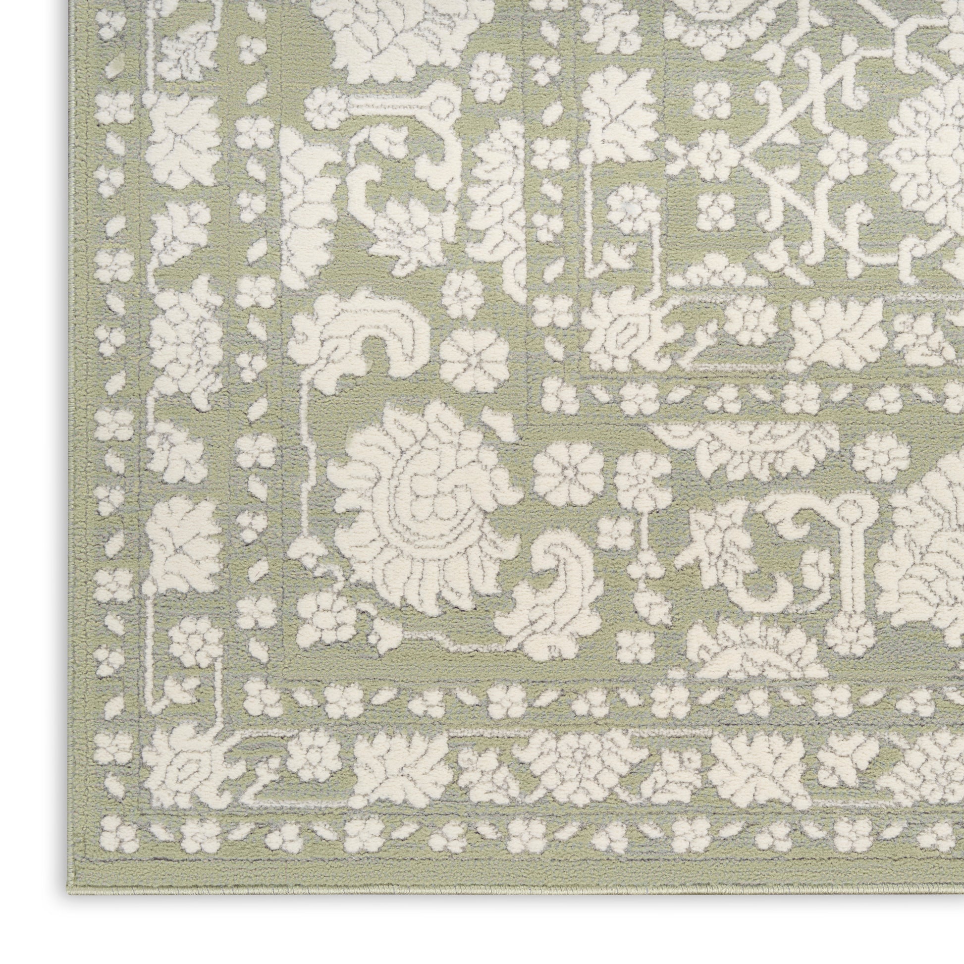 Sage green area rug with white embossed floral damask pattern and decorative border.