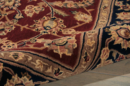 Red oriental rug with cream floral motifs, beige border and blue accents on a wooden floor.