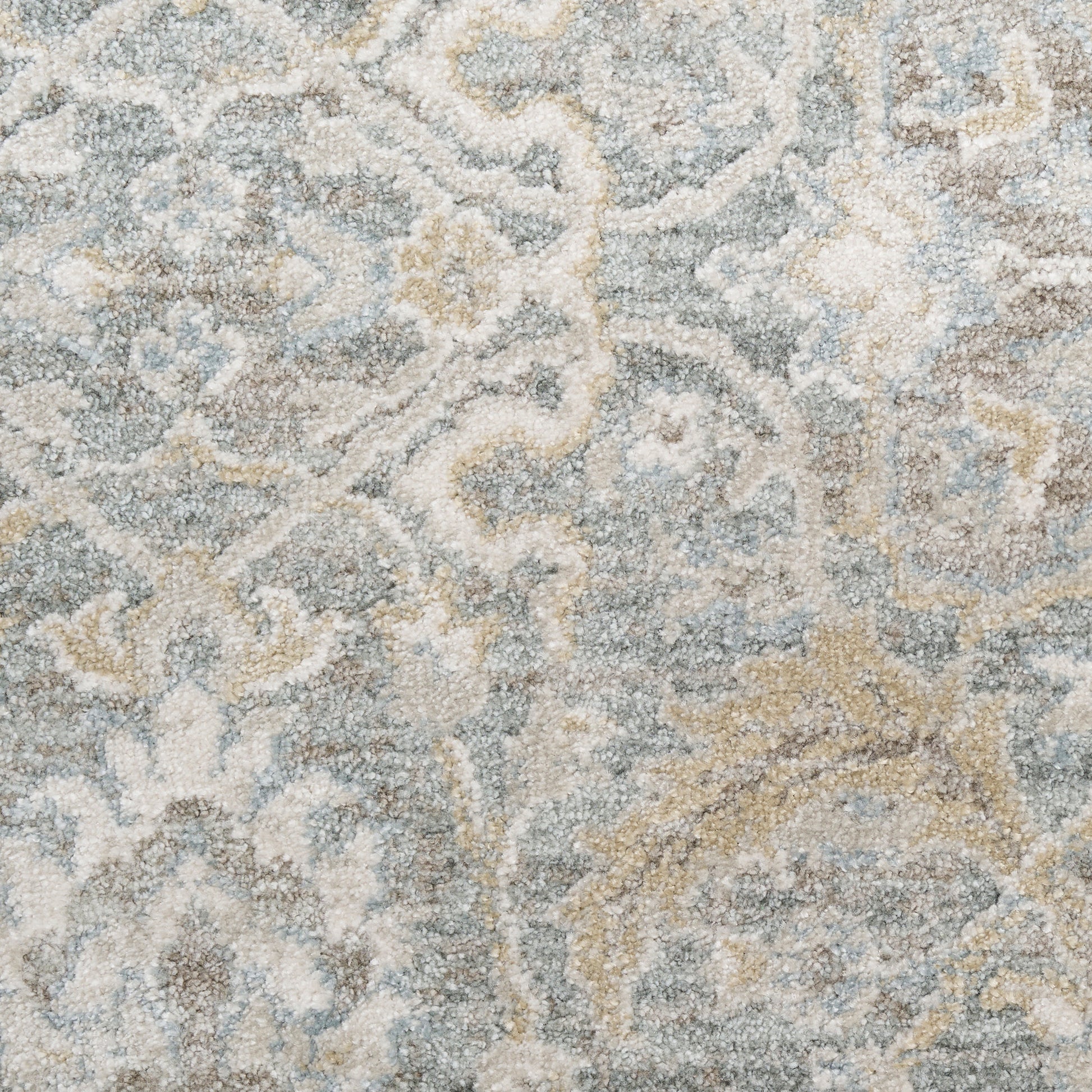 Distressed blue-gray and ivory patterned area rug with beige scrollwork; soft plush pile, oriental-inspired design.