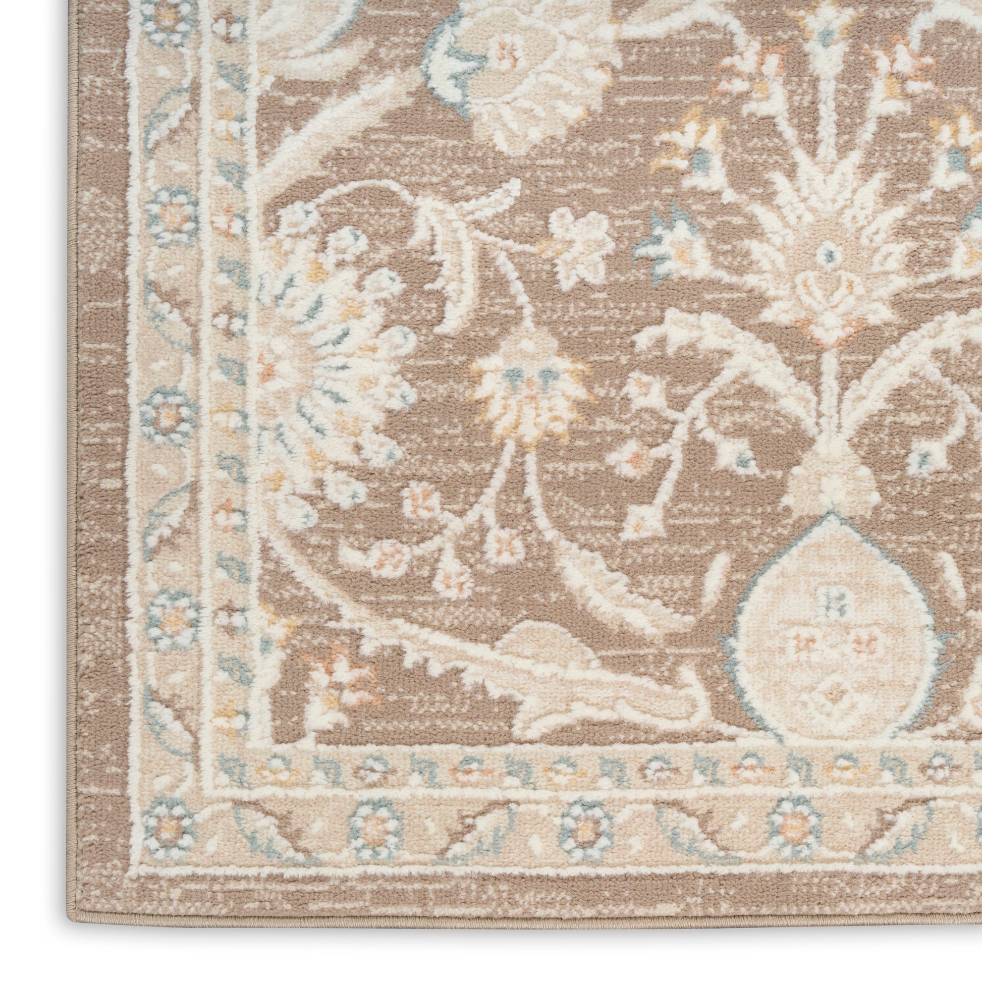 Close-up of a taupe floral area rug corner with ivory and pale blue accents and an ornate border.