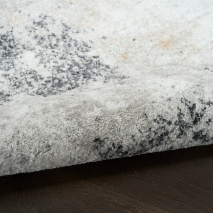 Plush shag rug in ivory-gray with charcoal abstract pattern, edge shown on dark wood floor.