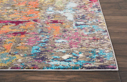 Abstract multicolor area rug with beige base and bright orange, pink and turquoise patches; light edge binding on wood floor.