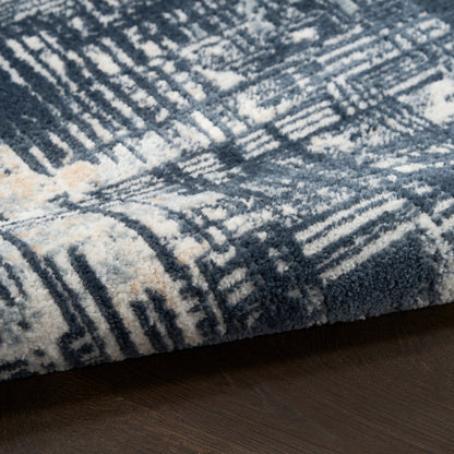 Blue & ivory geometric shag rug with plush pile on dark wood floor.