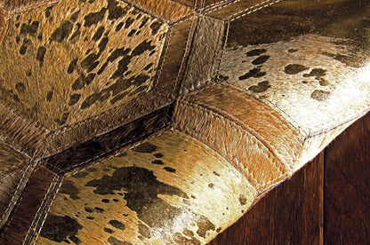 Cowhide patchwork rug in tan, brown and black panels with heavy stitching.