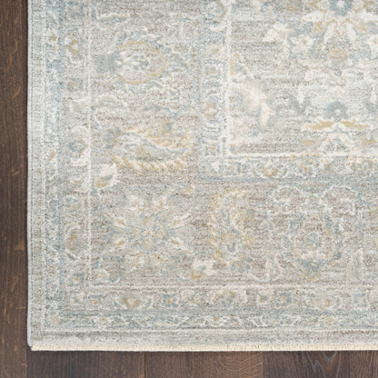 Light gray-blue oriental area rug with ivory motifs and decorative border on dark wood floor.