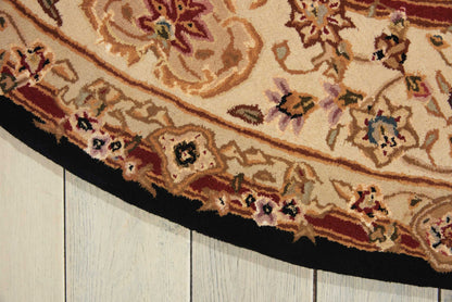 Round ornate beige rug with red, gold floral patterns and a black border laid on a light wooden floor.