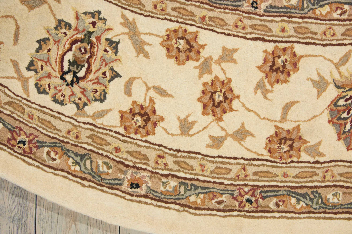 Close-up of cream oriental rug with brown and tan floral motifs and blue border detailing.