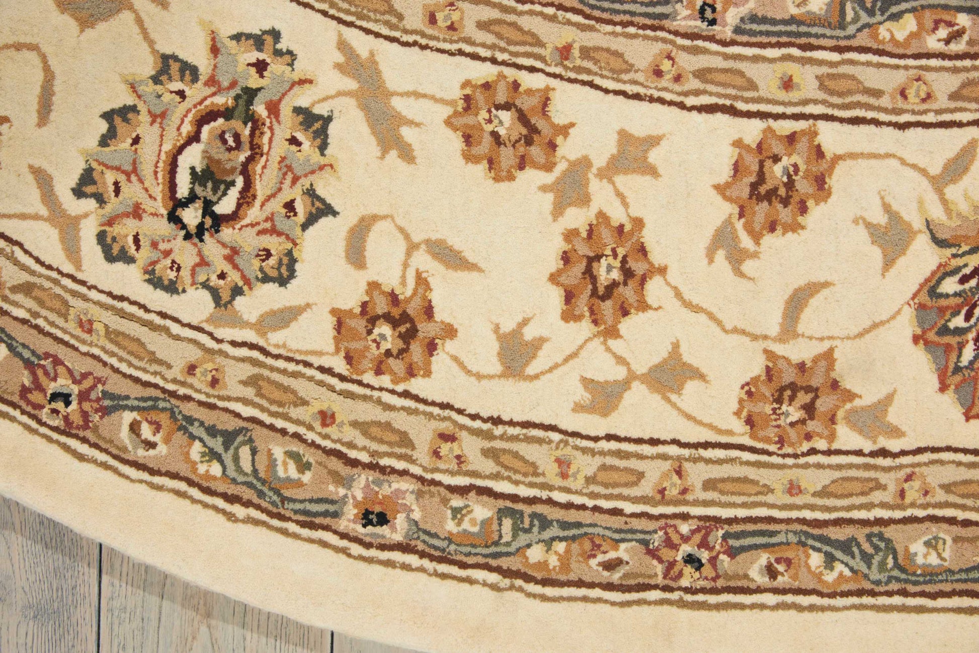 Close-up of cream oriental rug with brown and tan floral motifs and blue border detailing.