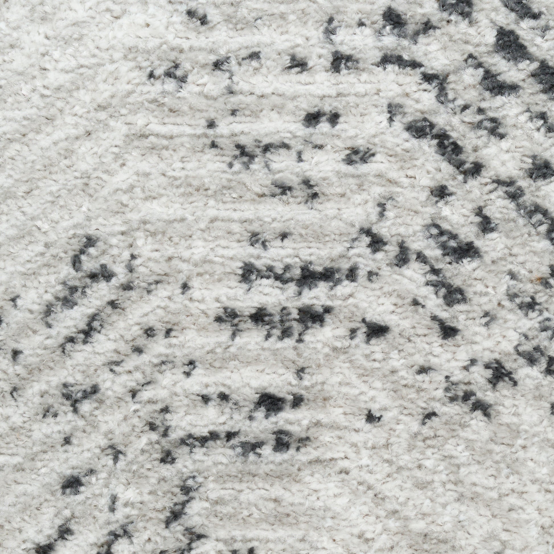 Close-up of cream shag rug with subtle dark gray abstract pattern, plush soft pile.