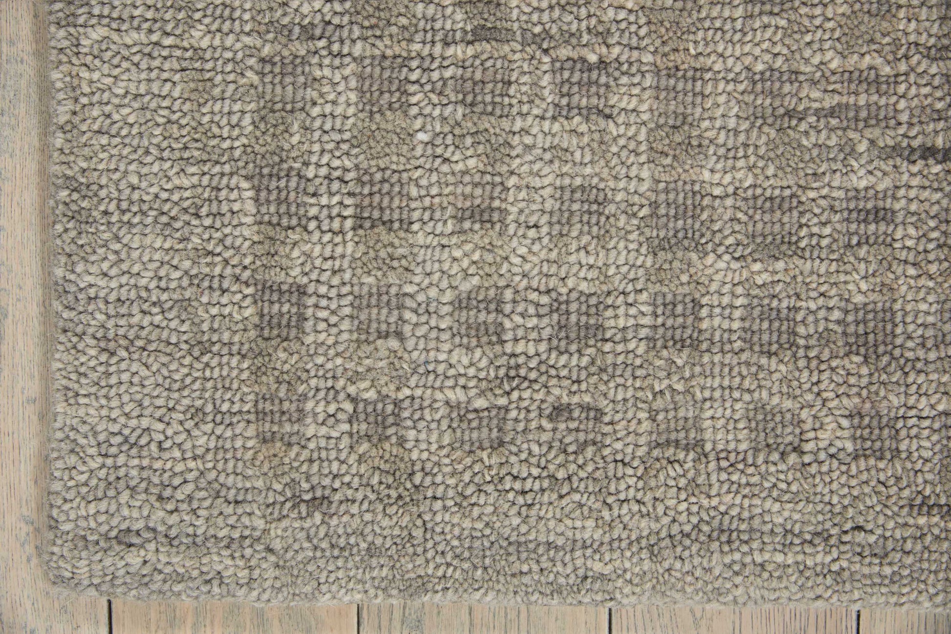 Neutral gray shag rug with a subtle geometric pattern on a light wood floor.