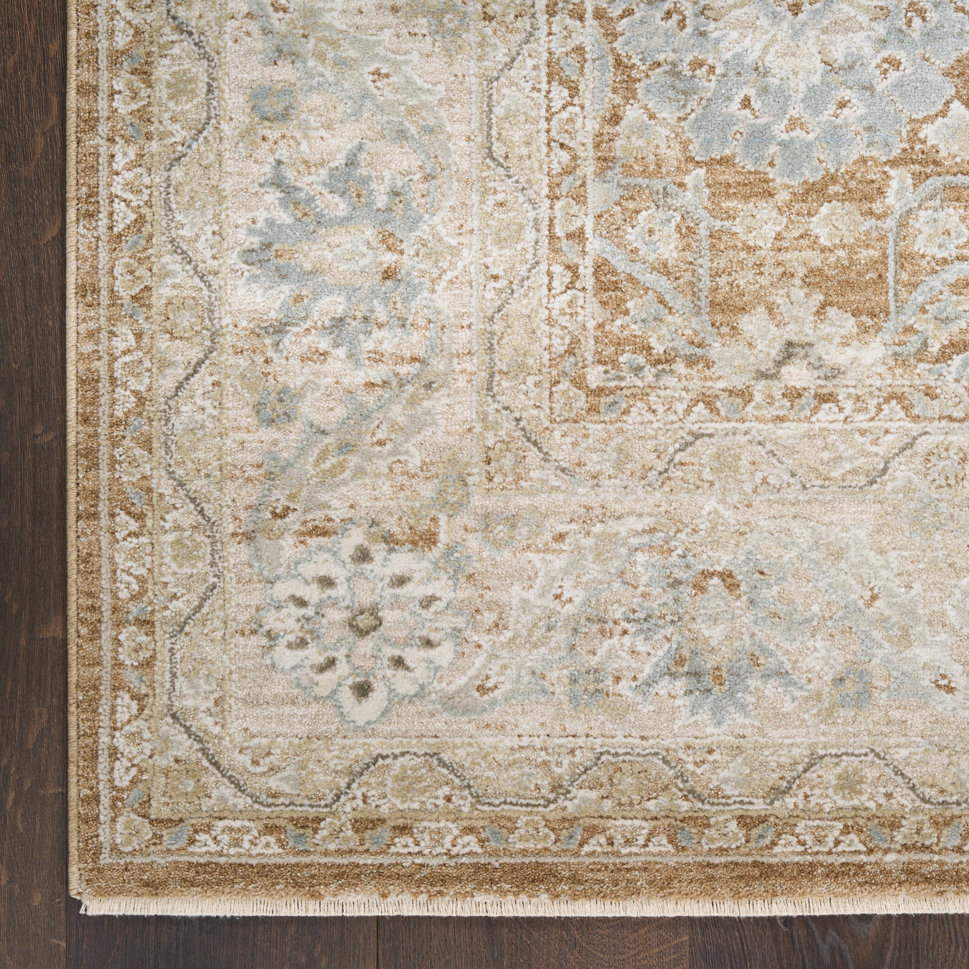 Light beige oriental rug with blue-gray accents and ornate floral border on dark wood floor.