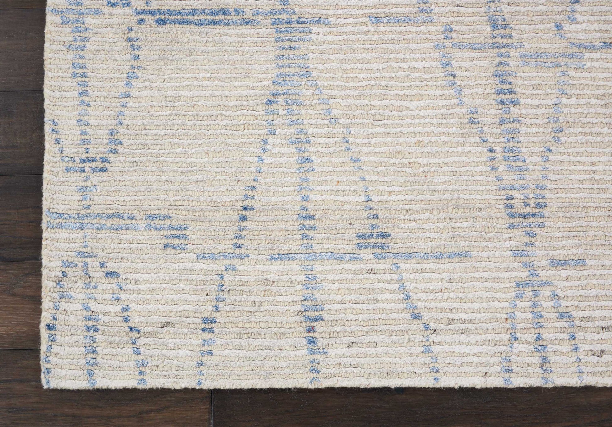 Cream flat-weave rectangular rug with pale blue geometric lines on dark wood floor