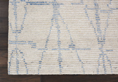 Cream flat-weave rectangular rug with pale blue geometric lines on dark wood floor