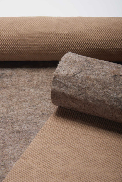 Neutral 12' rug runner with a textured surface; a gray stone rests on rolled tan burlap over brown felt.