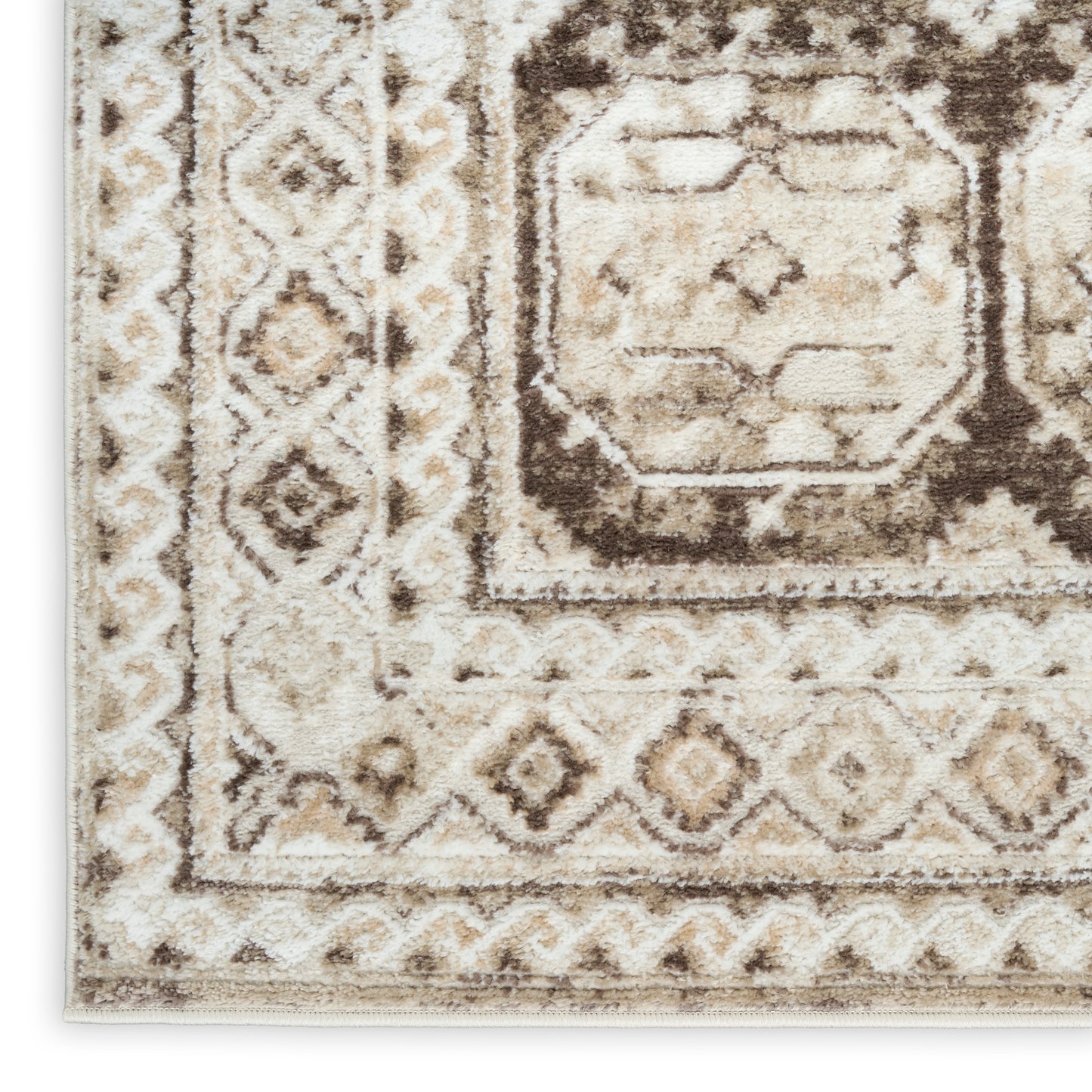 Beige and brown oriental rug close-up with distressed geometric medallion and diamond border