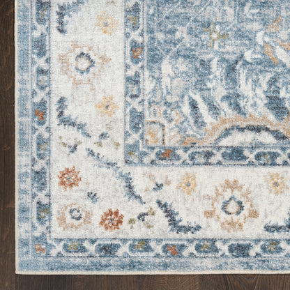 Blue and ivory Persian-style area rug with floral border on dark wood floor