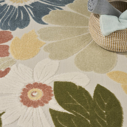 Floral patterned area rug with large white bloom, olive leaves in beige and yellow tones; woven texture with a basket on the edge.