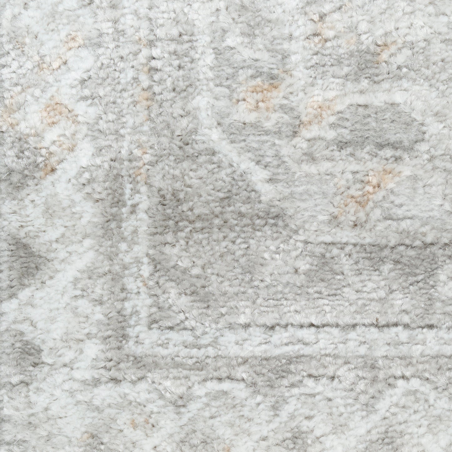 Close-up of a light gray plush shag rug with beige accents and a rectangular border pattern.