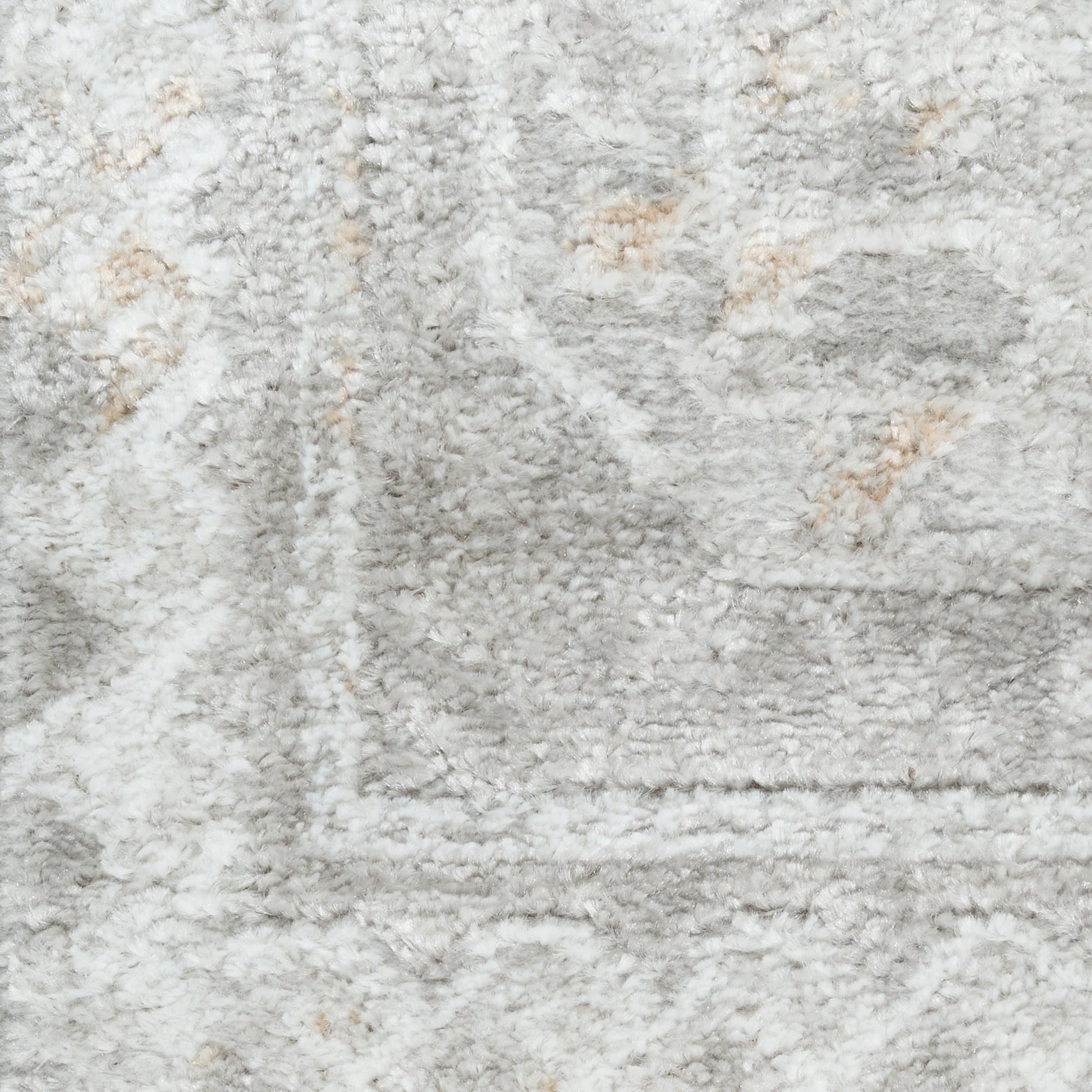 Close-up of a light gray plush shag rug with beige accents and a rectangular border pattern.