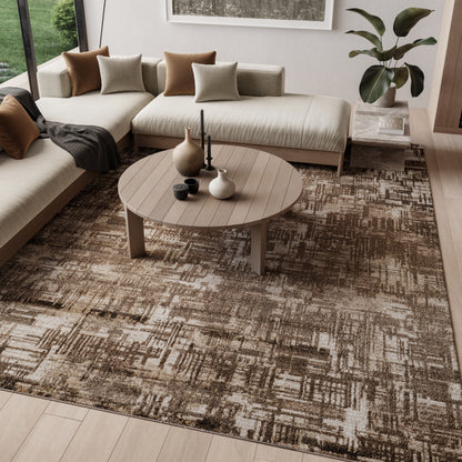 Neutral beige sectional sofa with tan & beige cushions, round wood coffee table, ceramic vases & candles, brown geometric rug, potted plant.