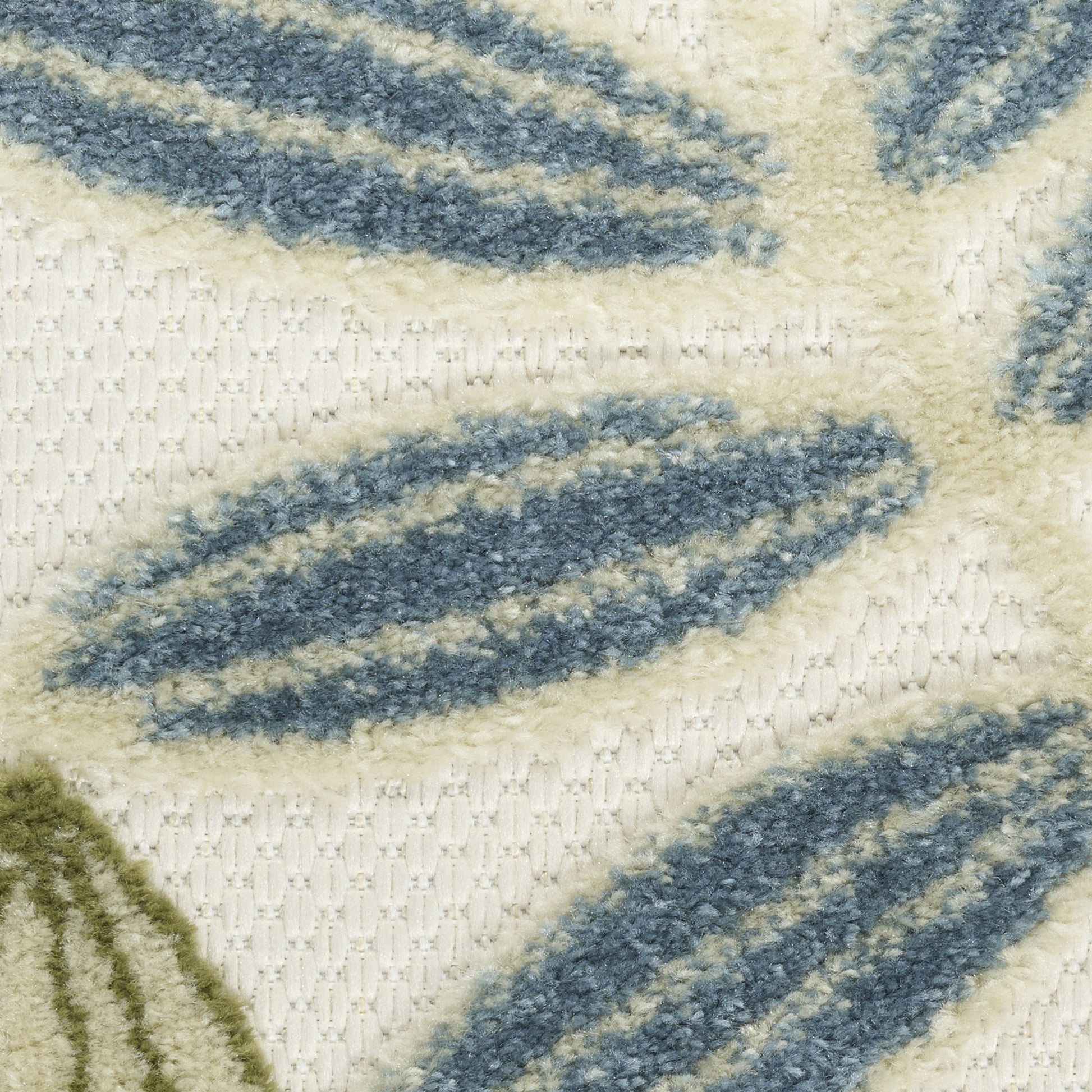 Cream woven rug with blue elongated leaf motifs and subtle green accents; soft textured floor decor.