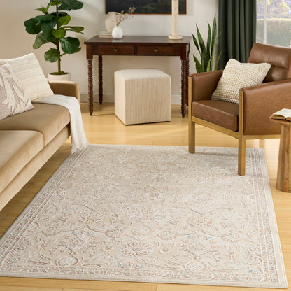 Light ornate rug on a cozy living room floor, with a beige sofa, brown leather chair, a wooden console table, and a beige pouf visible.