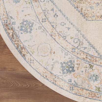Round ivory rug with distressed blue and tan floral medallion pattern on wood floor.